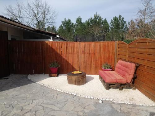 une terrasse avec une chaise rouge et une clôture en bois dans l'établissement Bassin d'Arcachon - studio Ares -, à Arès