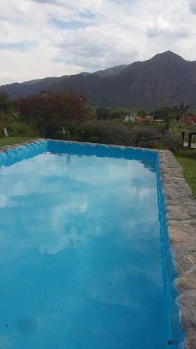 una piscina azul de agua con montañas en el fondo en Cabañas Cafayate II en Cafayate