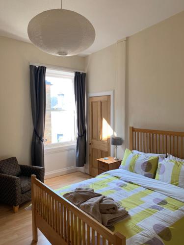 a bedroom with a bed and a chair and a window at Bass Rock Beachside Flat in North Berwick
