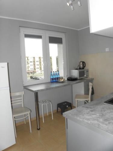 a kitchen with a counter with chairs and a table at Apartament „STARY RYNEK” Słupsk in Słupsk