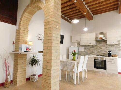 a kitchen with an archway and a table and chairs at Otello Guest House in Montalcino