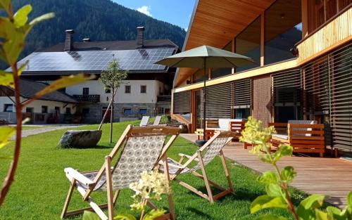 a patio with chairs and an umbrella on the grass at Stacherhof in Planca di Sopra