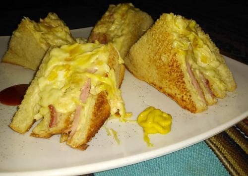 a white plate with a sandwich and some mustard at Monkeywasi Climbing Hostel in Huaraz