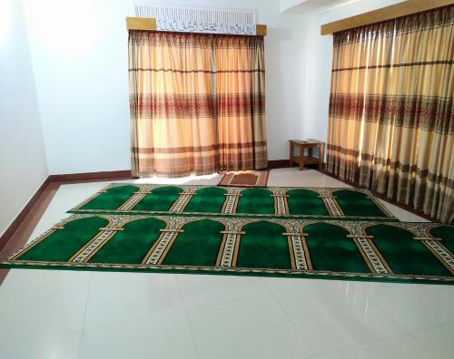 Schlafzimmer mit einem Bett und einem Fenster mit Vorhängen in der Unterkunft Hotel Cox's Hilton in Cox's Bazar