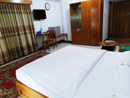 ein Schlafzimmer mit einem großen weißen Bett und einem TV in der Unterkunft Hotel Cox's Hilton in Cox's Bazar