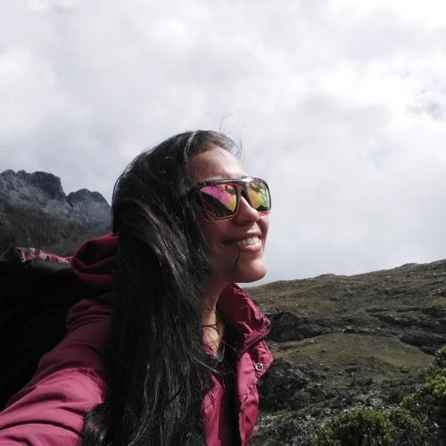 a woman wearing sunglasses sitting on top of a mountain at Monkeywasi Climbing Hostel in Huaraz