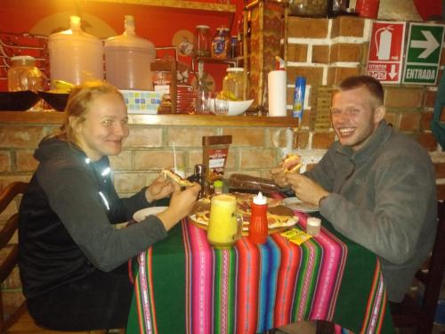 a man and woman sitting at a table eating food at Monkeywasi Climbing Hostel in Huaraz