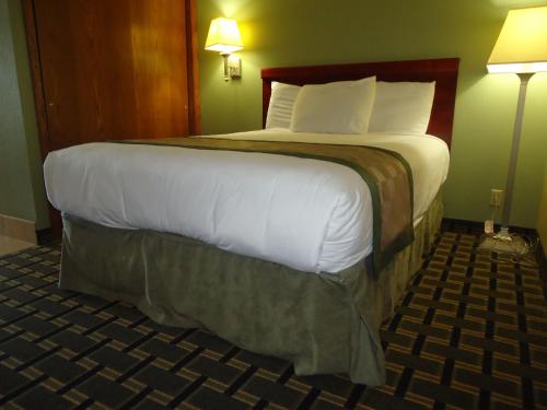 een groot bed in een hotelkamer met 2 lampen bij TownHouse Extended Stay Hotel Downtown in Lincoln