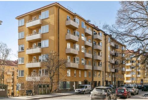 un gran edificio amarillo con coches estacionados frente a él en Central Stockholm with Free Airport Pickup en Estocolmo