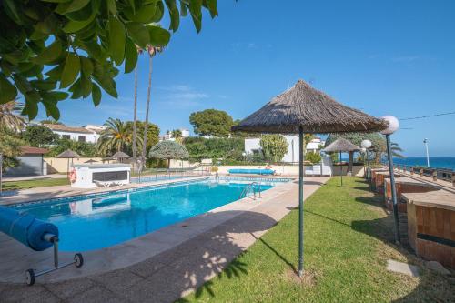 uma piscina com um guarda-sol e o oceano ao fundo em Aparto Residence Galetamar em Calpe