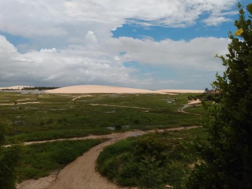 ジェリコアコアラにあるAmelinhas Houseの砂丘を背景にした野原の未舗装道路