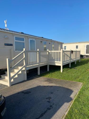 a mobile home with a porch and a fence at Cosy caravan in Hull