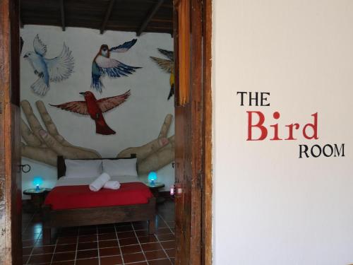 a room with a bed and birds on the wall at La Hacienda in San Gil