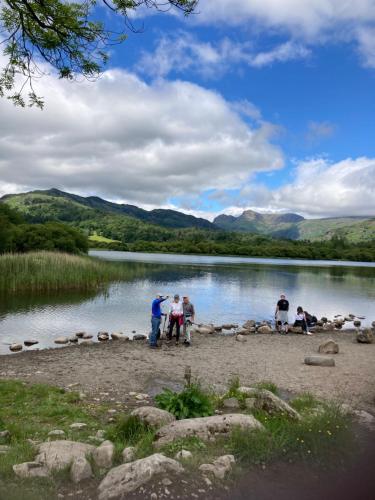 a group of people standing on the shore of a lake at Troutbeck Hot Tub Lodge 4 in Windermere