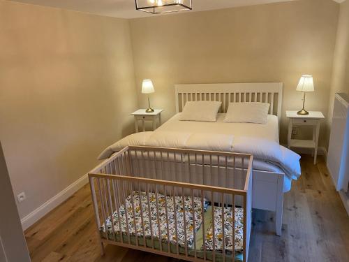 ein Schlafzimmer mit einem Bett, zwei Lampen und einem Kinderbett in der Unterkunft De Betze - Country Life in Geetbets