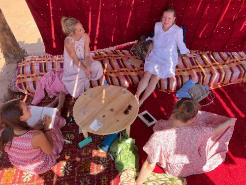 a group of people sitting on a bed in a tent at Bivouac Les Nomades & Foum zguid to chegaga tours in Foum Zguid