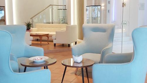 a living room with blue chairs and tables at Akrogiali Exclusive Hotel (Adults Only) in Polychrono