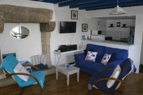 a living room with a blue couch and chairs at Gîte Charbonnerie in Moncontour