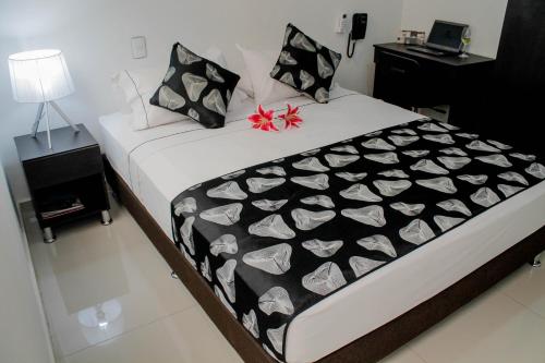 a bedroom with a bed with a black and white blanket at La Cabrera Hotel Boutique in Neiva
