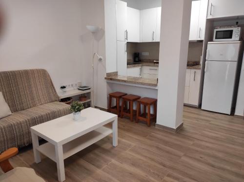 巴列格蘭雷的住宿－APARTAMENTO en PLAYA CALERA，带沙发和桌子的客厅以及厨房。
