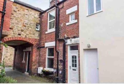 a brick building with a white door in front of it at The Nook, Morpeth Town in Morpeth