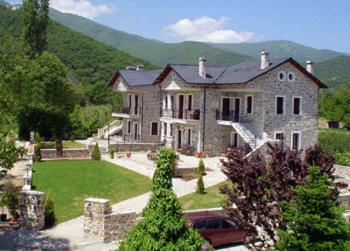 a large stone house with a landscaped yard in front of a mountain at Villa Kastanodasos in Emporio