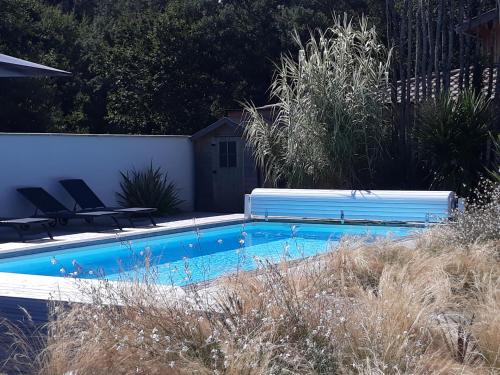 einen Pool mit zwei Stühlen und einer Bank in der Unterkunft B&B Les Villas de Gascogne in Lanton