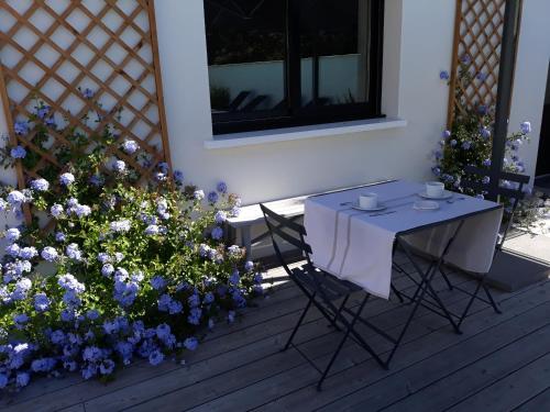 einen Tisch und Stühle auf einer Veranda mit Blumen in der Unterkunft B&B Les Villas de Gascogne in Lanton