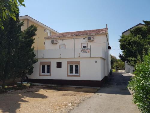 a large white house with a driveway at PORTA NOVALIS Rooms in Novalja