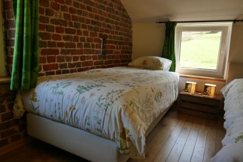 a bedroom with a bed and a brick wall at B&B La ferme de Berwausault in Herve