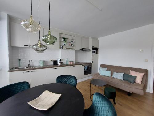 a kitchen and a living room with a table and chairs at Sea-cret, een sfeervol appartement aan zee in Blankenberge