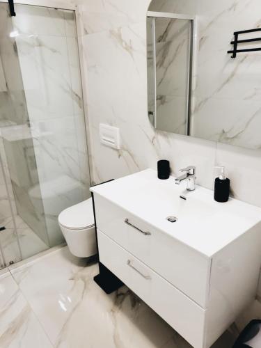 un bagno bianco con lavandino e WC di Stella Apartment a Sarandë