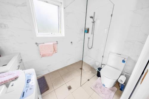 a white bathroom with a shower and a toilet at Cromwell Lite in Cooma