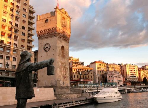 a clock tower with a statue next to a river at Don Pedro Beach House in Savona