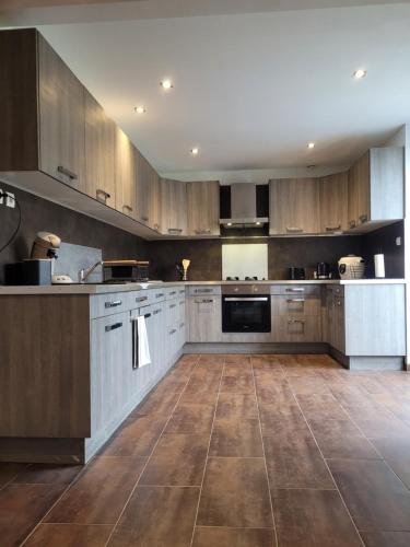 uma grande cozinha com armários de madeira e piso em azulejo em Un nid pour la nuit em Bransles