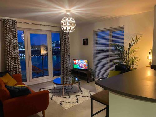 ein Wohnzimmer mit einem Kronleuchter und ein Wohnzimmer mit einem TV in der Unterkunft Luxury 2 Bedroom waterfront apartment with balcony in Newport