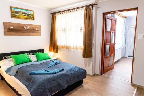 a bedroom with a large bed with green pillows at Bor, Villa, Sóstó in Nyíregyháza