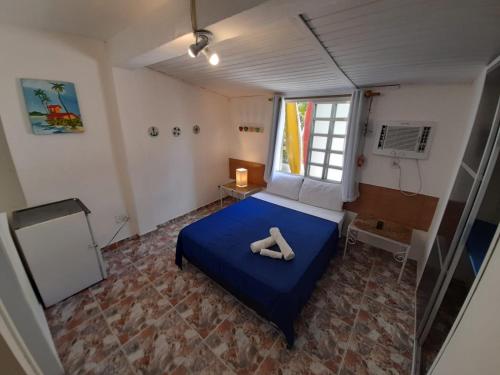 a bedroom with a blue bed with a pair of shoes on it at Suites Geriba in Búzios