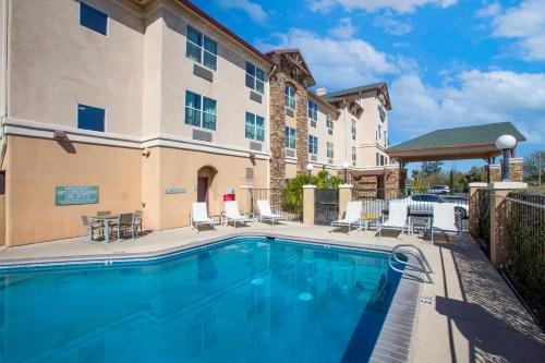 a pool in front of a building with chairs and a table at Country Inn & Suites by Radisson, Tucson City Center AZ in Tucson