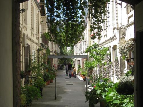 Une allée avec des plantes et des gens qui la descendent dans l'établissement Cité Pilleux - Charming Studio in a flowery pedestrian lane, à Paris