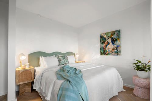 a white bedroom with a bed and a painting on the wall at Houston Beachfront Apartments in Gold Coast
