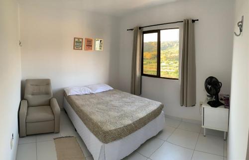 1 dormitorio con 1 cama, 1 silla y 1 ventana en Duplex com 02 Suítes e Ar-Condicionados en Bananeiras