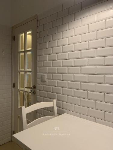 a white table and a chair in front of a brick wall at Nº7 Sacadura Cabral in Guarda