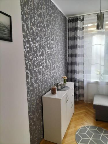 a living room with a white cabinet and a wall at Apartament ADA in Koszalin