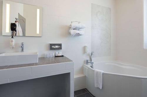 a white bathroom with a sink and a tub at Best Western Central Hotel in Tours