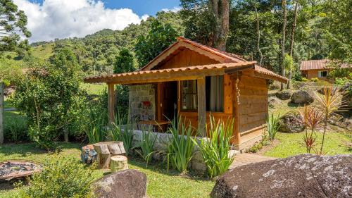 a small wooden cabin with a porch in a garden at Chalés Das Estrelas in Visconde De Maua