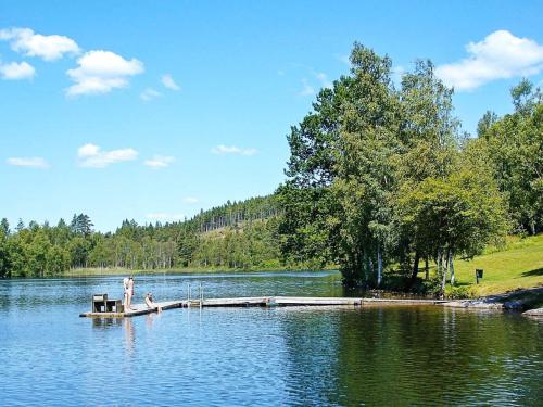 a person sitting on a dock in the middle of a lake at 5 person holiday home in Fjärås-By Traum in Fjärås