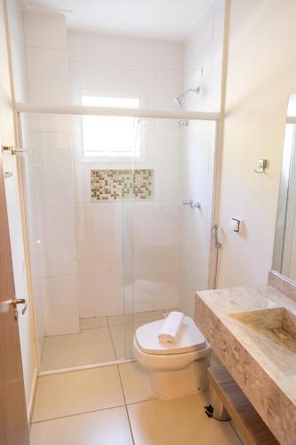 a white bathroom with a shower and a toilet at Village de Charme - 2km do Capivari in Campos do Jordão