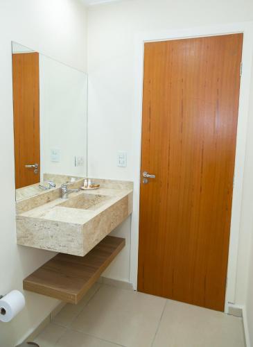 a bathroom with a sink and a wooden door at Village de Charme - 2km do Capivari in Campos do Jordão