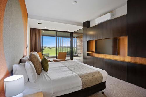 - une chambre avec un grand lit et une télévision dans l'établissement Peppers Moonah Links Resort, à Fingal